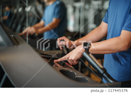 finger pushing start button on treadmill at fitness gym exercise finger pushing start button on treadmill at fitness gym exercise 117445376