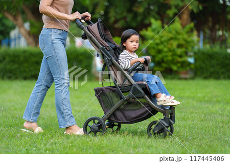 mother pushing toddler baby stroller and walking in park mother pushing toddler baby stroller and walking in park 117445406