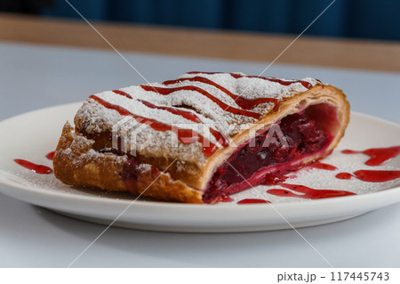 Dessert strudel with cherry and ice cream on a white plate Dessert strudel with cherry and ice cream on a white plate 117445743