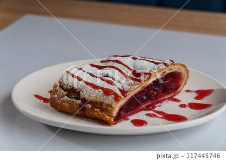 Dessert strudel with cherry and ice cream on a white plate 117445746