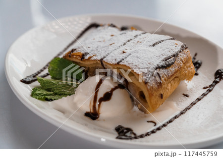 Dessert strudel with chocolate and ice cream on a white plate Dessert strudel with chocolate and ice cream on a white plate 117445759