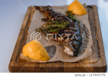 Dorado fish baked with lemon on a barbecue on a wooden board Dorado fish baked with lemon on a barbecue on a wooden board 117445770