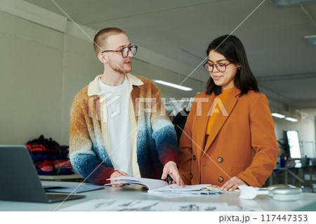 Fashion designers discussing sketches Fashion designers discussing sketches 117447353