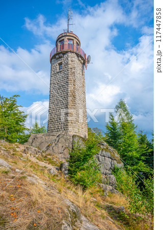 Rising against a blue sky, the stone lookout tower on Prosecsky Hreben in the Jizera Mountains stands as a point of interest for visitors seeking panoramic views. 117447858