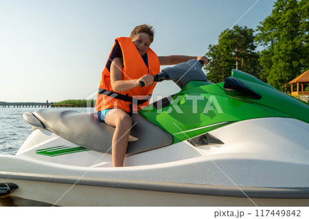 Young rider navigates a watercraft on calm waters during sunset 117449842