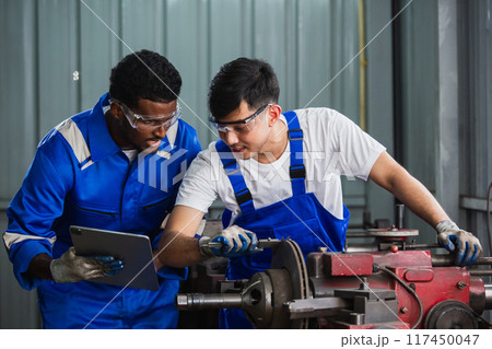 Two Man engineer using digital tablet check up usage of brake disc grinder. Two Man engineer using digital tablet check up usage of brake disc grinder. 117450047