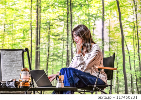 ワーケーション アウトドアチェアに座ってノートパソコンを操作する若い女性 ワーケーション アウトドアチェアに座ってノートパソコンを操作する若い女性 117450231