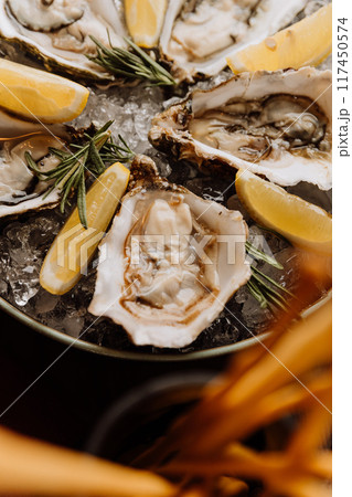 Fresh oysters with lemon on ice, ideal for gourmet seafood dishes and fine dining experiences 117450574