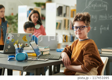 Portrait of funny young boy wearing glasses looking at camera in school library during computer class for children copy space Portrait of funny young boy wearing glasses looking at camera in school library during computer class for children copy space 117451095