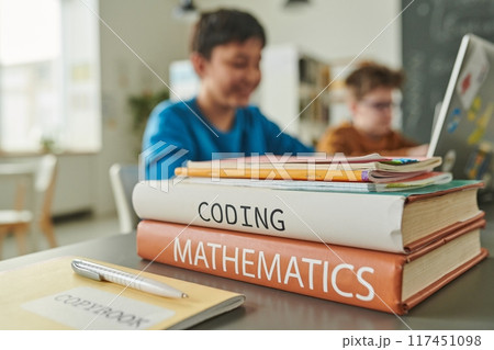 Close up of textbooks on coding and mathematics on table in school library with children in background copy space Close up of textbooks on coding and mathematics on table in school library with children in background copy space 117451098