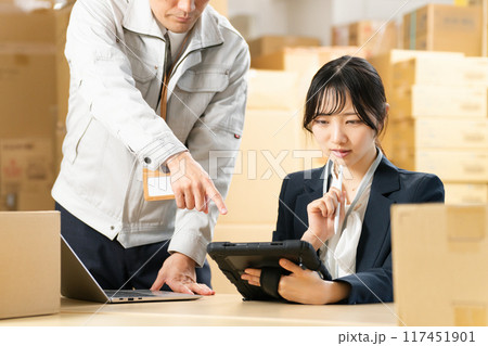 タブレットを見つめる女性と指示する作業着の男性　物流事務　イメージ 117451901