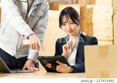 タブレットを見つめる女性と指示する作業着の男性　物流事務　イメージ 117451902