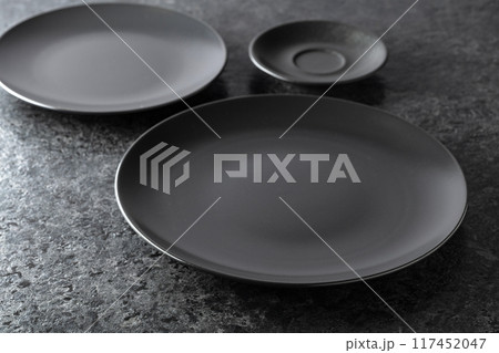 Black ceramic plates on a black stone table. 117452047