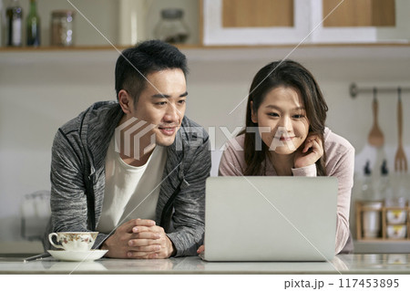 young asian couple using laptop computer together at home young asian couple using laptop computer together at home 117453895