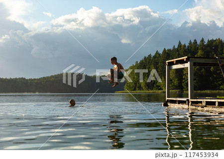Teenage boys jumping in lake water at summer holiday. Teenage boys jumping in lake water at summer holiday. 117453934