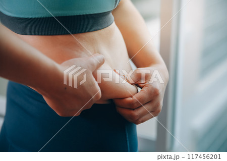 fat woman, fat belly, chubby, obese woman hand holding excessive belly fat with measure tape, woman diet lifestyle concept 117456201
