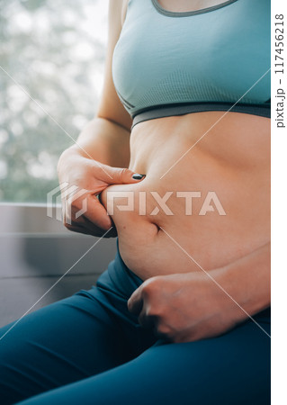 fat woman, fat belly, chubby, obese woman hand holding excessive belly fat with measure tape, woman diet lifestyle concept 117456218