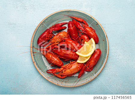 Delicious cooked crayfish with lemon slices on rustic blue plate top view 117456565