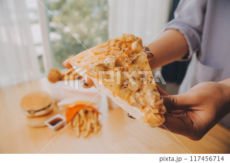 Cropped image of woman holding pizza slice at restaurant Cropped image of woman holding pizza slice at restaurant 117456714