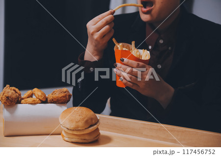 Asian woman holding french fries and eating happily in restaurant 117456752