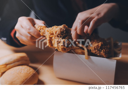 close up focus woman hand hold fried chicken for eat,girl with fast food concept 117456765