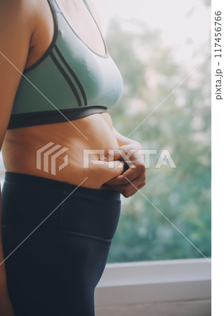 fat woman, fat belly, chubby, obese woman hand holding excessive belly fat with measure tape, woman diet lifestyle concept 117456766