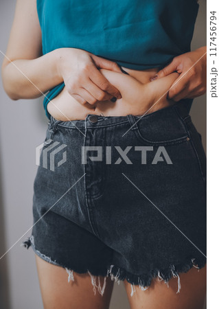 fat woman, fat belly, chubby, obese woman hand holding excessive belly fat with measure tape, woman diet lifestyle concept 117456794