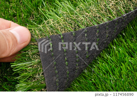 Fingers Lifting Edge of Artificial Grass 117456890