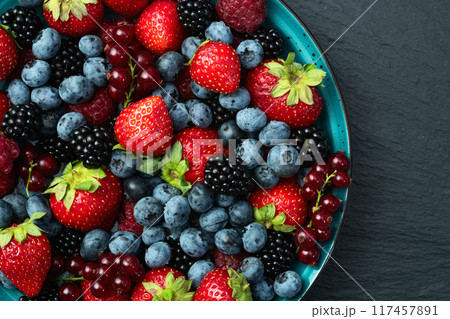 Mix of ripe colorful berries in bowl photography . Blueberry , strawberry , raspberry , blackberry and red currant . Top view 117457891