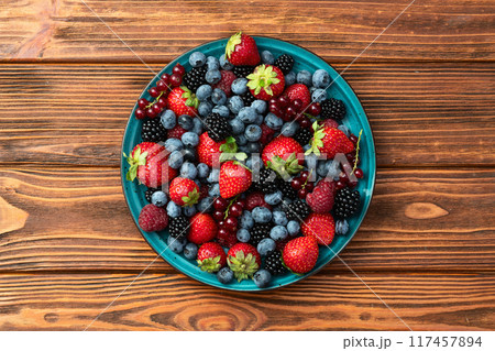 Mix of ripe colorful berries in bowl photography . Blueberry , strawberry , raspberry , blackberry and red currant . Top view 117457894