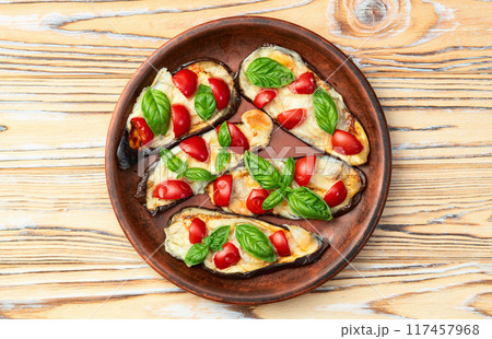 Italian mini pizza . Aubergine (eggplant ) with mozzarella cheese and basil . On rustic background Italian mini pizza . Aubergine (eggplant ) with mozzarella cheese and basil . On rustic background 117457968