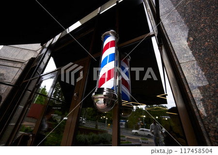 Barber shop exterior with vintage pole reflecting in glass during late afternoon 117458504