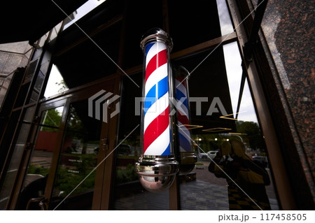 Traditional barber pole displayed outside a barber shop during the day Traditional barber pole displayed outside a barber shop during the day 117458505