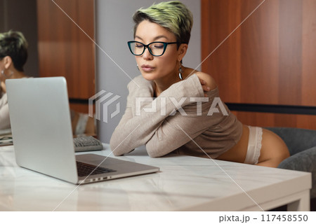 A beautiful girl with short hair in her underwear is sitting sexy in a room at a laptop, working and chatting online A beautiful girl with short hair in her underwear is sitting sexy in a room at a laptop, working and chatting online 117458550