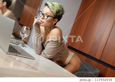 A beautiful girl with short hair in her underwear is sitting sexy in a room at a laptop, working and chatting online 117458556