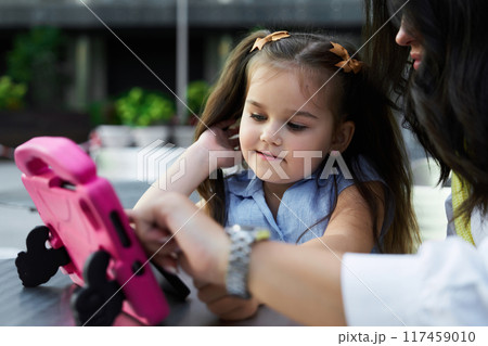 Mother and daughter enjoying interactive screen time at a park on a sunny day Mother and daughter enjoying interactive screen time at a park on a sunny day 117459010