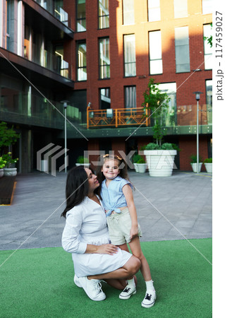 Mother and daughter enjoying a sunny afternoon in a modern urban courtyard 117459027