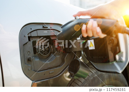 a girl charges her electric car at a charging station, Environmentally friendly energy sources 117459281