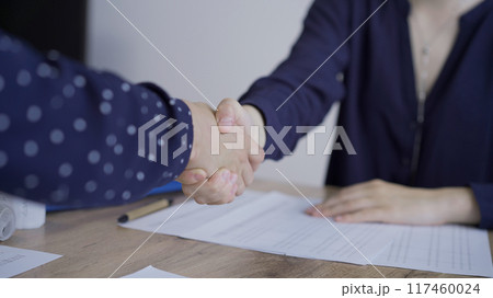 Accountants or auditors shaking hands after reviewing financial documents in office. Audit and taxes, handshake as a symbol of agreement 117460024
