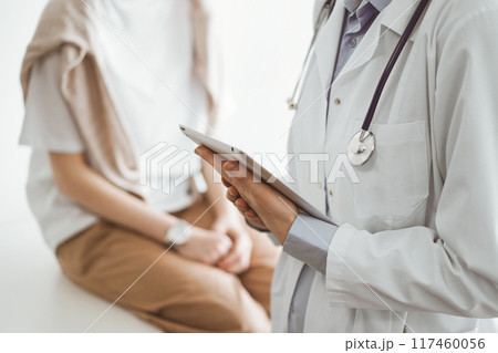 Doctor and patient discussing perfect health exam results. Friendly physician keeping tablet computer with her hands near a young woman. Medicine concept 117460056