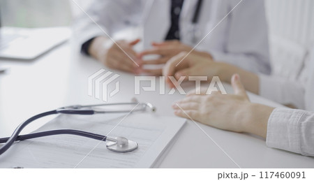Stethoscope in focus while doctor and a patient gesturing with their hands during a consultation in the clinic. Medicine concept 117460091