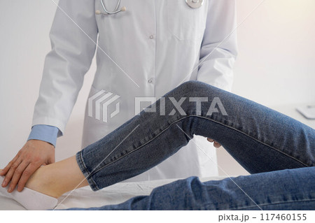 Doctor and patient are at the medical inspection in clinic. Orthopedic examines the knee of a young woman. Medicine concept Doctor and patient are at the medical inspection in clinic. Orthopedic examines the knee of a young woman. Medicine concept 117460155