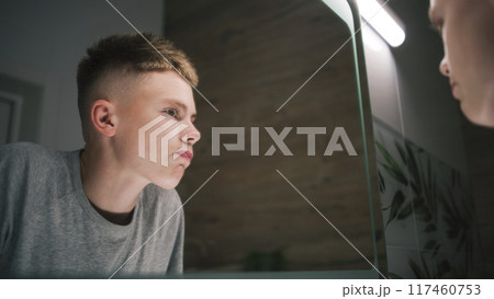 Teenager stands near wash basin and makes hairstyle Teenager stands near wash basin and makes hairstyle 117460753