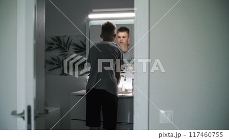 Caucasian boy washes face with cold water, wipes using towel 117460755