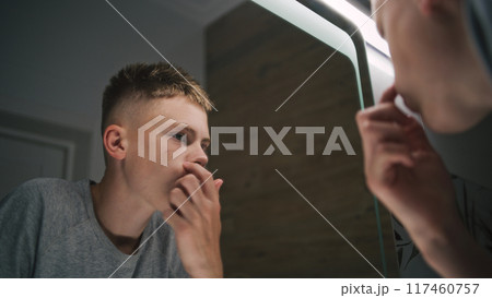 Teenager stands near wash basin and makes hairstyle 117460757