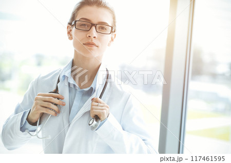 Beautiful woman doctor with stethoscope smiling charmingly and ready to help patients in sunny hospital. Medicine concept Beautiful woman doctor with stethoscope smiling charmingly and ready to help patients in sunny hospital. Medicine concept 117461595
