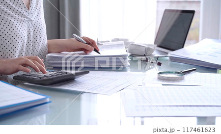 Business woman accountant or auditor reviewing financial data in office. Professional analyzing paper reports and using calculators. Audit and taxes Business woman accountant or auditor reviewing financial data in office. Professional analyzing paper reports and using calculators. Audit and taxes 117461623