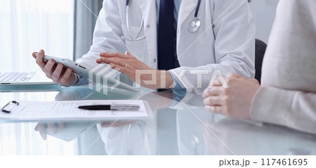 Doctor is consulting patient in modern clinic. Healthcare professional discusses medical information with a woman, using a tablet computer. Medicine concept Doctor is consulting patient in modern clinic. Healthcare professional discusses medical information with a woman, using a tablet computer. Medicine concept 117461695