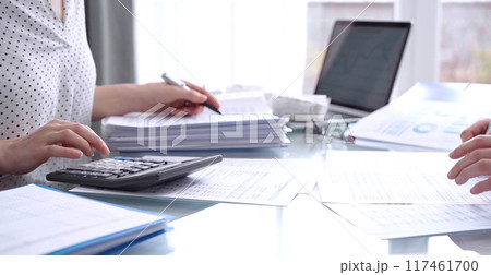 Business people, accountants or auditors reviewing financial data in office. Two professionals analyzing paper reports and using calculators. Audit and taxes 117461700