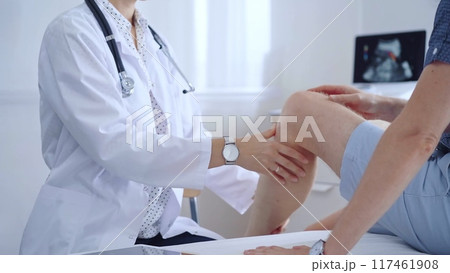 Doctor is carefully examining a patient's knee, providing personalized care and support. Medicine and orthopedic concept 117461908